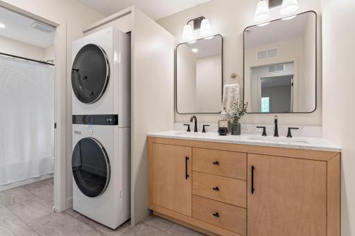 A full bathroom serves the upper level, featuring a double vanity and a separate wet-room complete with a tiled tub/shower, allowing for added functionality and convenience during busy mornings. The bathroom also includes a stacked washer and dryer.