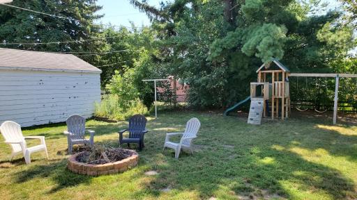 Peaceful fenced yard with play area and burning pit.