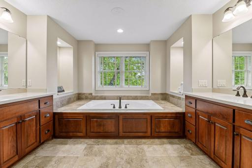 The primary bath offers a large walk-in shower, soaking tub, generous vanity space, and a calm, private setting.