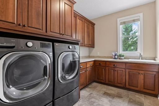A spacious laundry room with extensive cabinetry, countertop workspace, and utility sink combines function with everyday convenience.