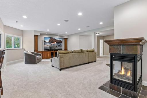 Designed for gathering, the finished lower-level amusement room offers generous living space anchored by a dramatic three-sided gas fireplace.