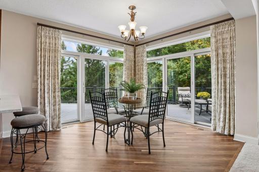 Sun-filled informal dining framed by two sets of 3-door patio sliders with transoms, opening directly to the maintenance-free deck and wooded backyard.
