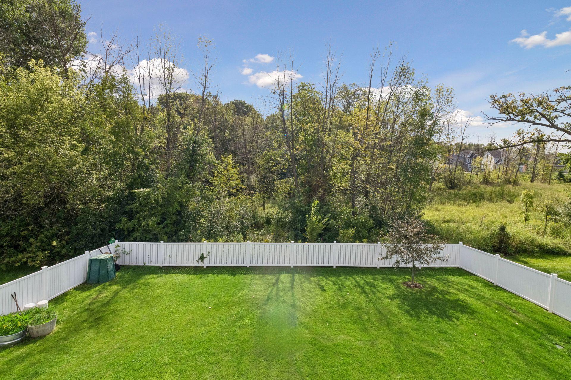 Fenced rear yard with wooded area beyond
