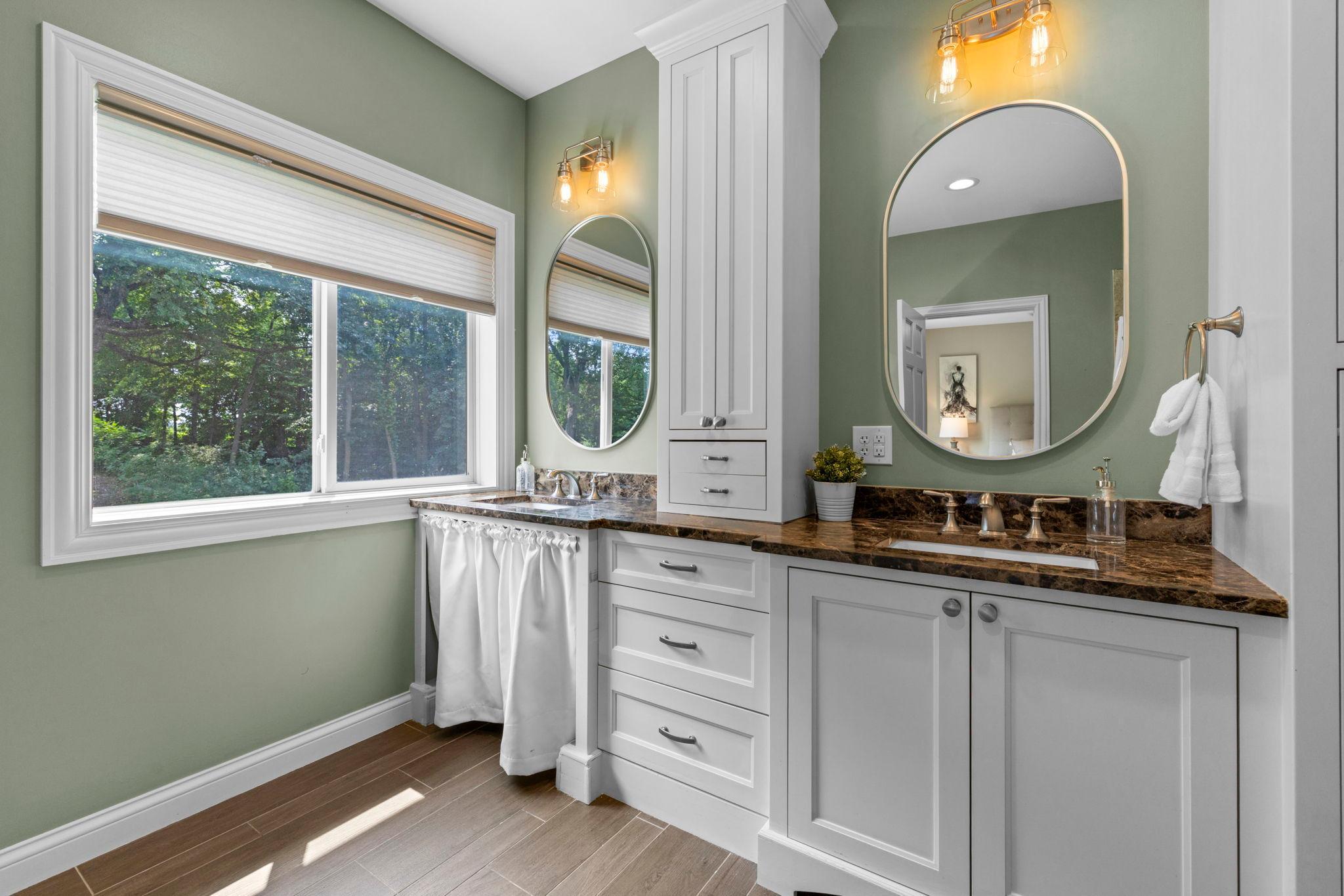 Primary ensuite bathroom featuring accessible dual vanities, including one roll-under sink for added accessibility.