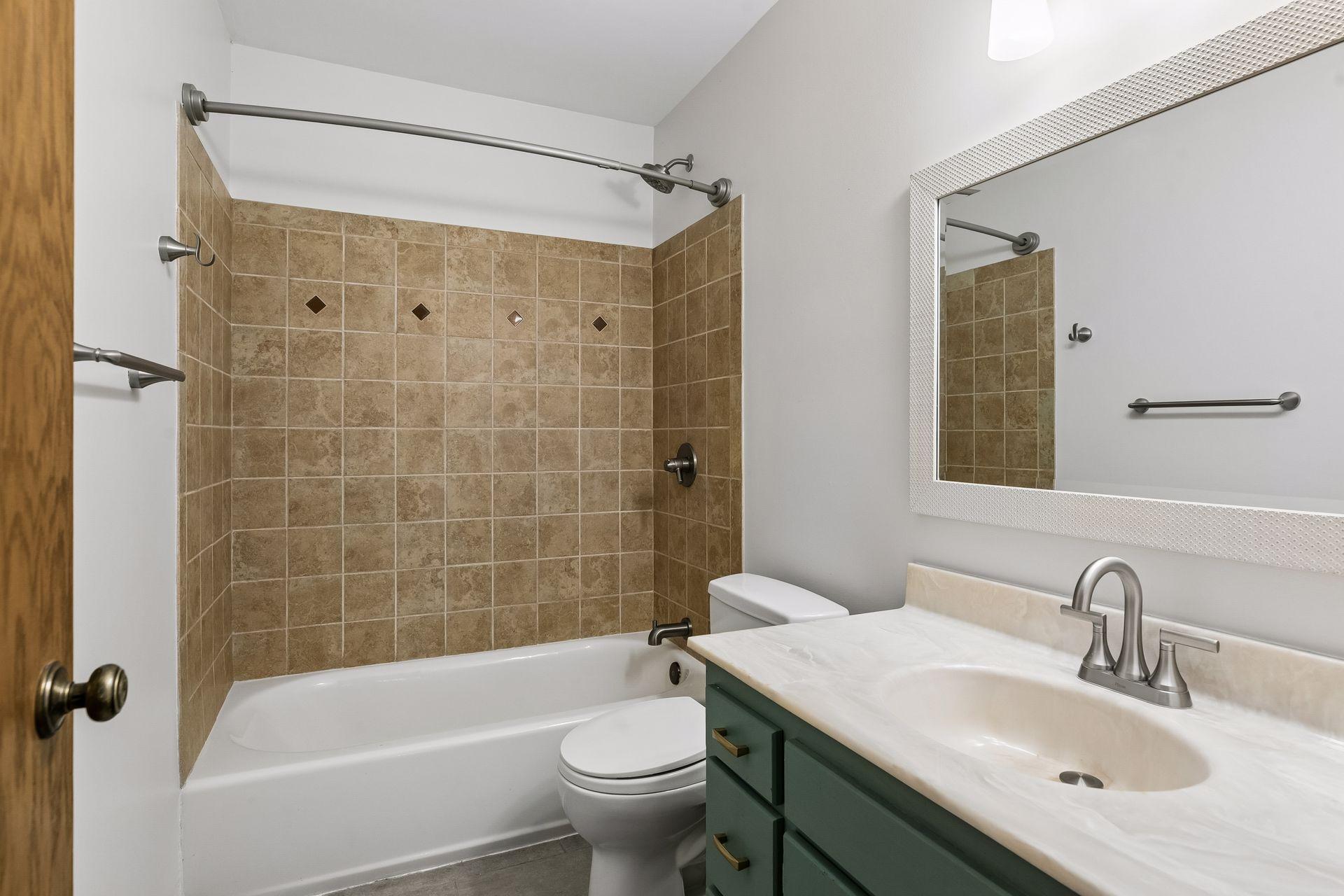 Upper-level full bath featuring a tiled tub surround, updated vanity, and modern fixtures.