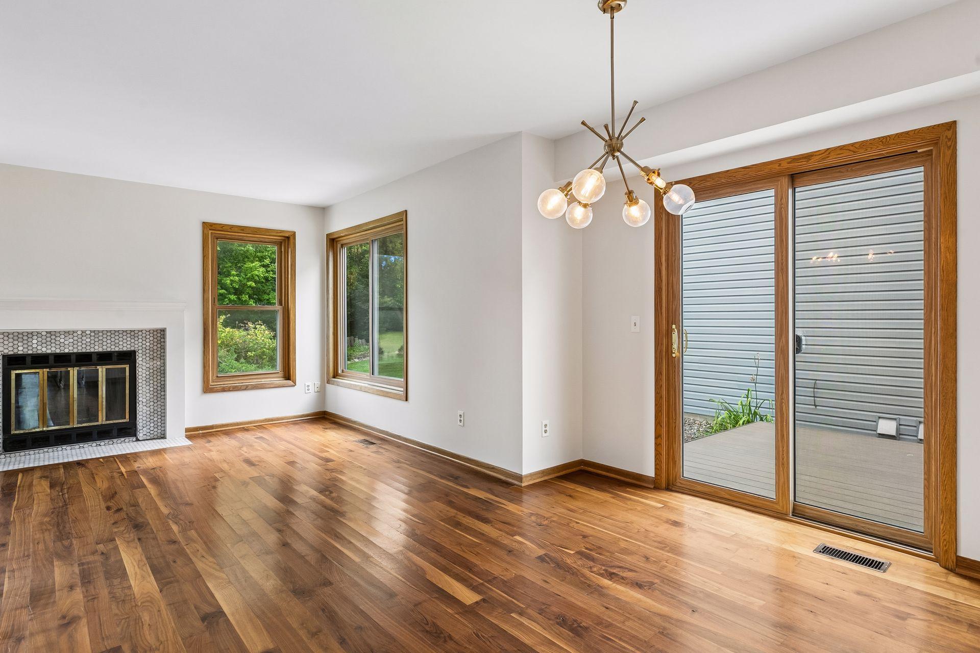 Sun-filled dining area featuring beautiful hardwood floors, a cozy fireplace, and sliding glass doors leading to the maintenance-free deck.