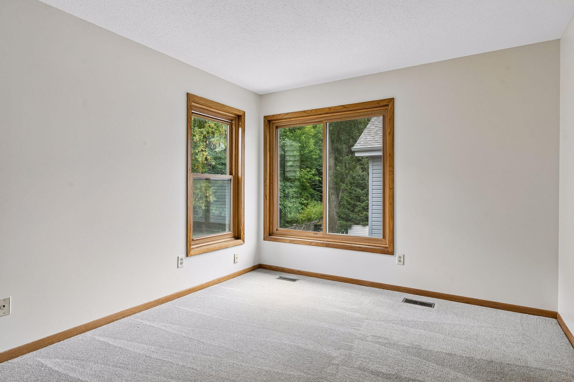 Generously sized upper-level bedroom with new carpet and large windows bringing in plenty of natural light