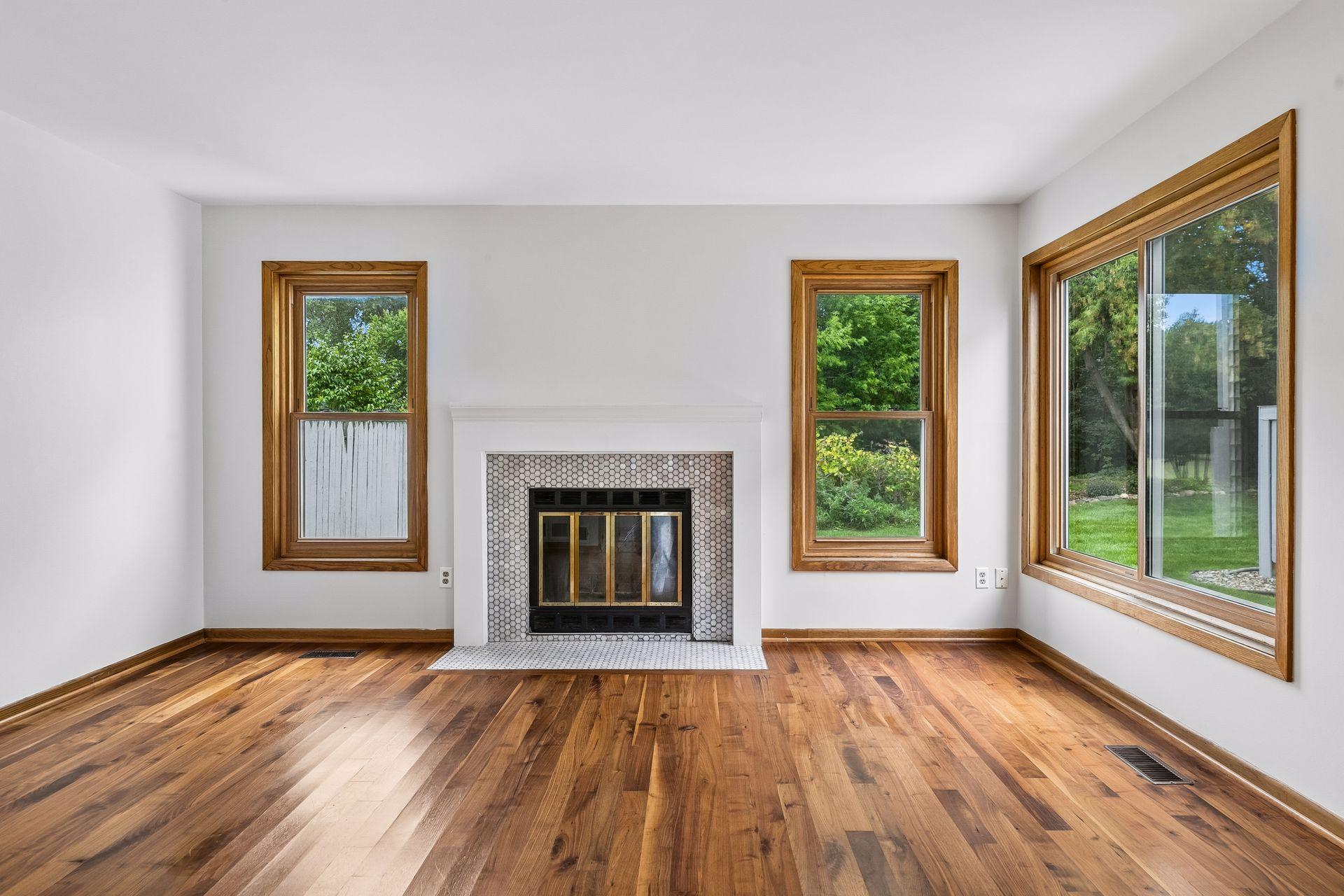 Bright and inviting living room featuring beautiful hardwood floors, a cozy fireplace, and large windows overlooking the private backyard.