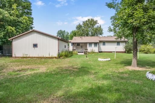 Rear view of the home and garage showcasing the generous yard and space between neighboring properties.