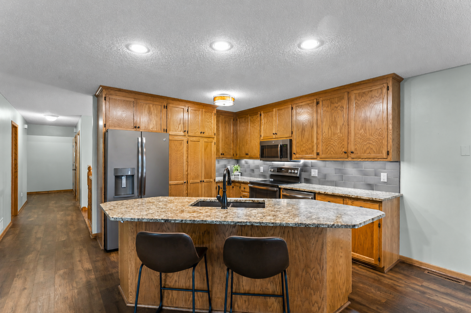 The adjoining kitchen offers abundant cabinetry for storage and a large center island with breakfast bar seating for additional prep space or gathering.