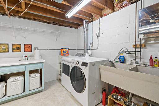 The lower-level laundry room offers a dedicated workspace with front-loading washer and dryer, a double utility sink and counter space for sorting, folding and everyday household tasks.