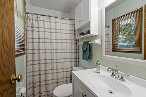 The primary ensuite bathroom offers convenient privacy with a full tub and shower, bright vanity, built-in storage and a window bringing natural light into the space.