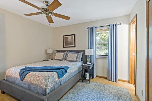 The main-level primary bedroom offers a comfortable retreat with hardwood floors, neutral finishes, a ceiling fan and natural light from the window.