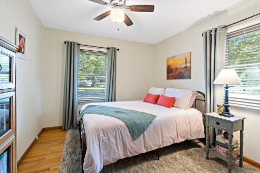 The third main-level bedroom features windows on two walls, creating a bright and airy feel. Hardwood floors and neutral finishes make this space ready to personalize.