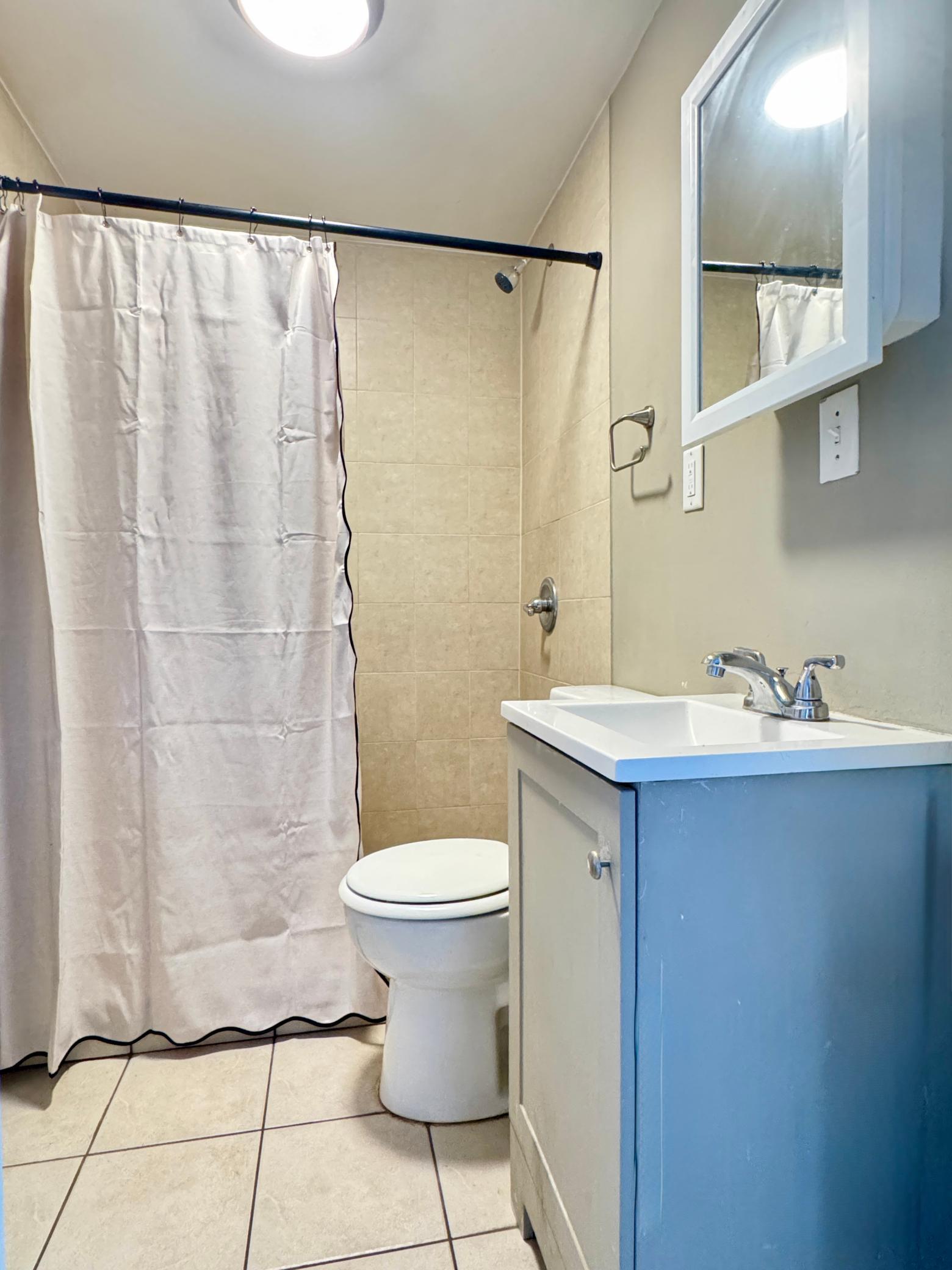 Main-level full bathroom with shower and vanity storage.