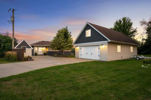 The property includes the home, an expansive heated 4-car garage with finished bonus space above, and two additional storage sheds, including the pictured matching shed complete with electricity.