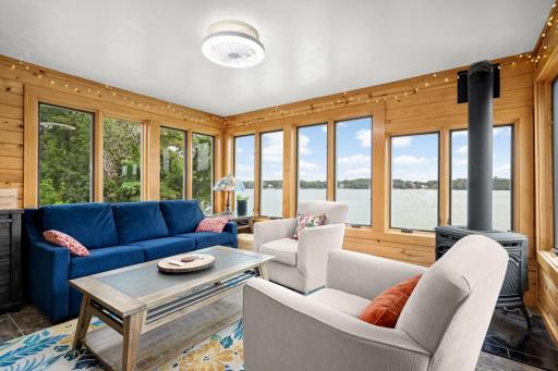 Walls of windows fill the sunroom with natural light, complemented by a cozy gas-burning fireplace.