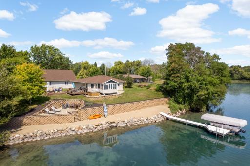 Lakeside of the property featuring a sandy beach, paver patio, tiered deck, and yard space.