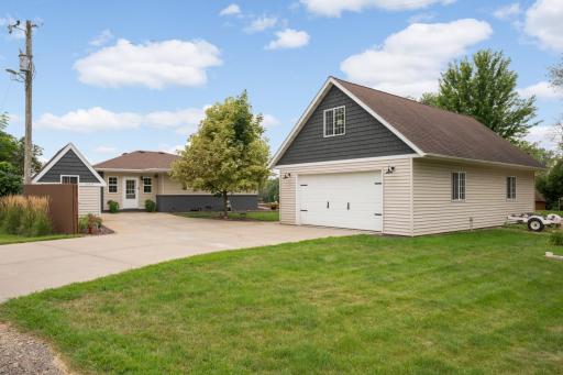 The property includes the home, an expansive heated 4-car garage with finished bonus space above, and two additional storage sheds, including the pictured matching shed complete with electricity.