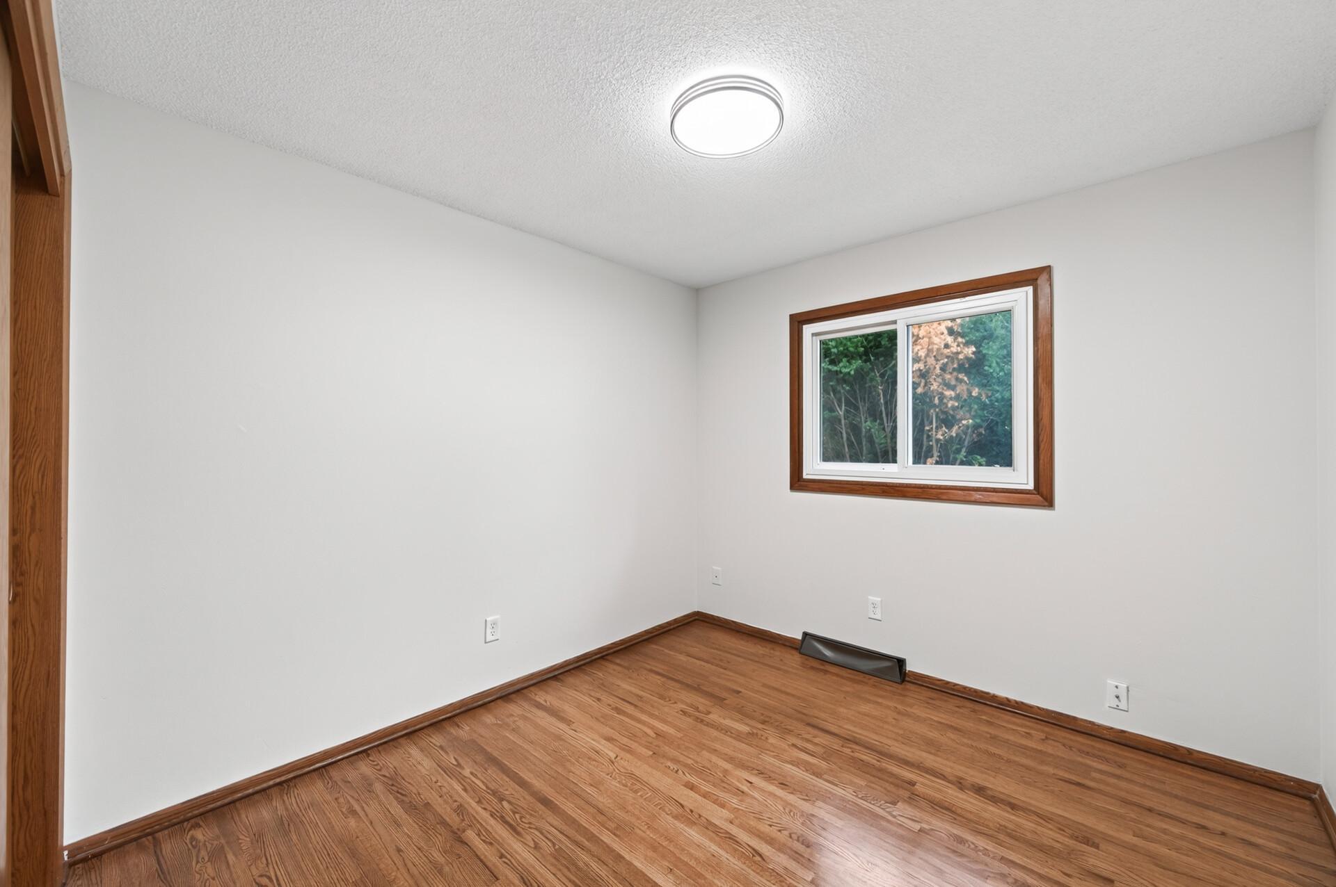 Comfortable bedroom with refinished floors and natural light.