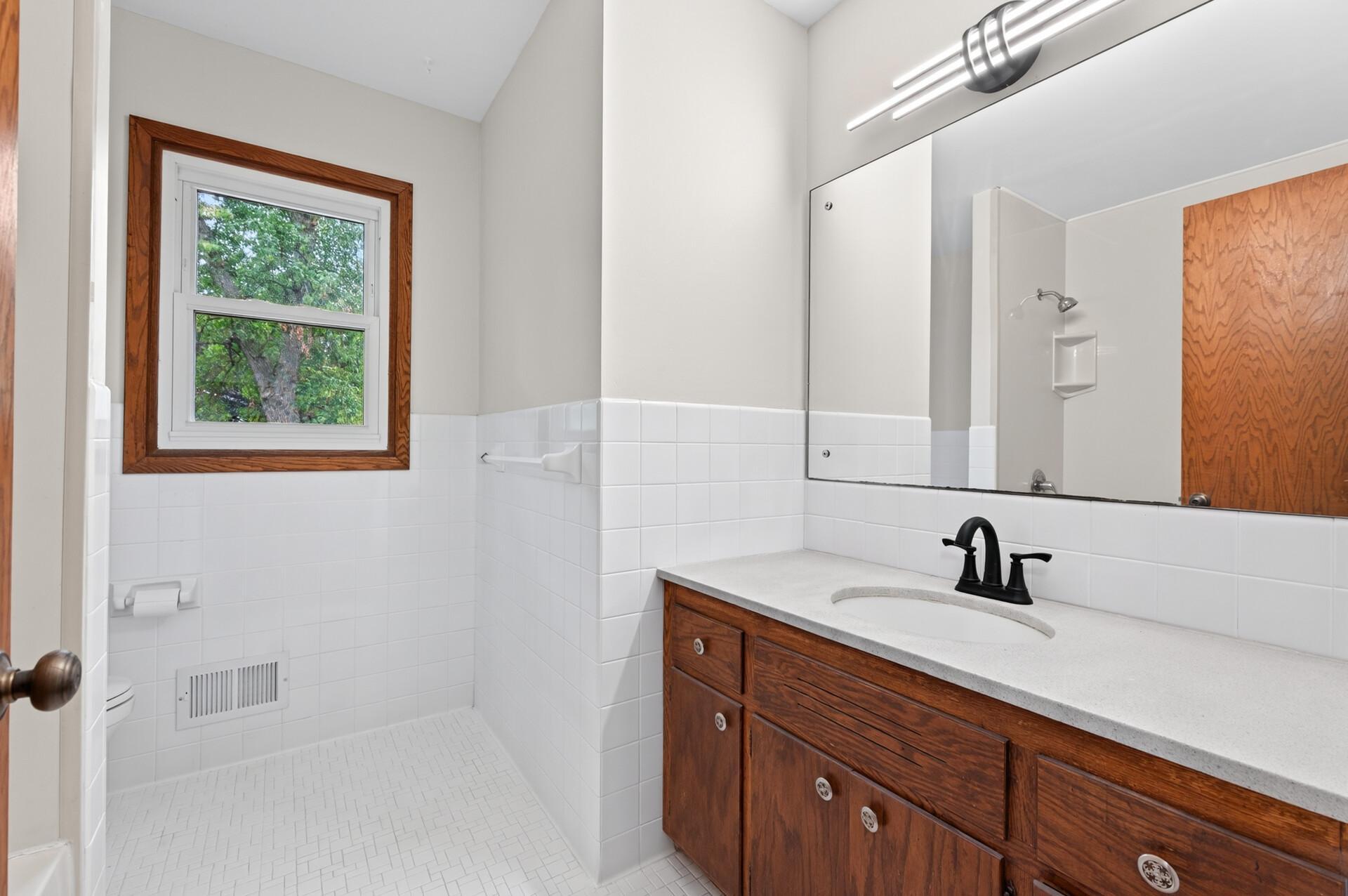 Full bathroom with sleek lighting and clean white tile.