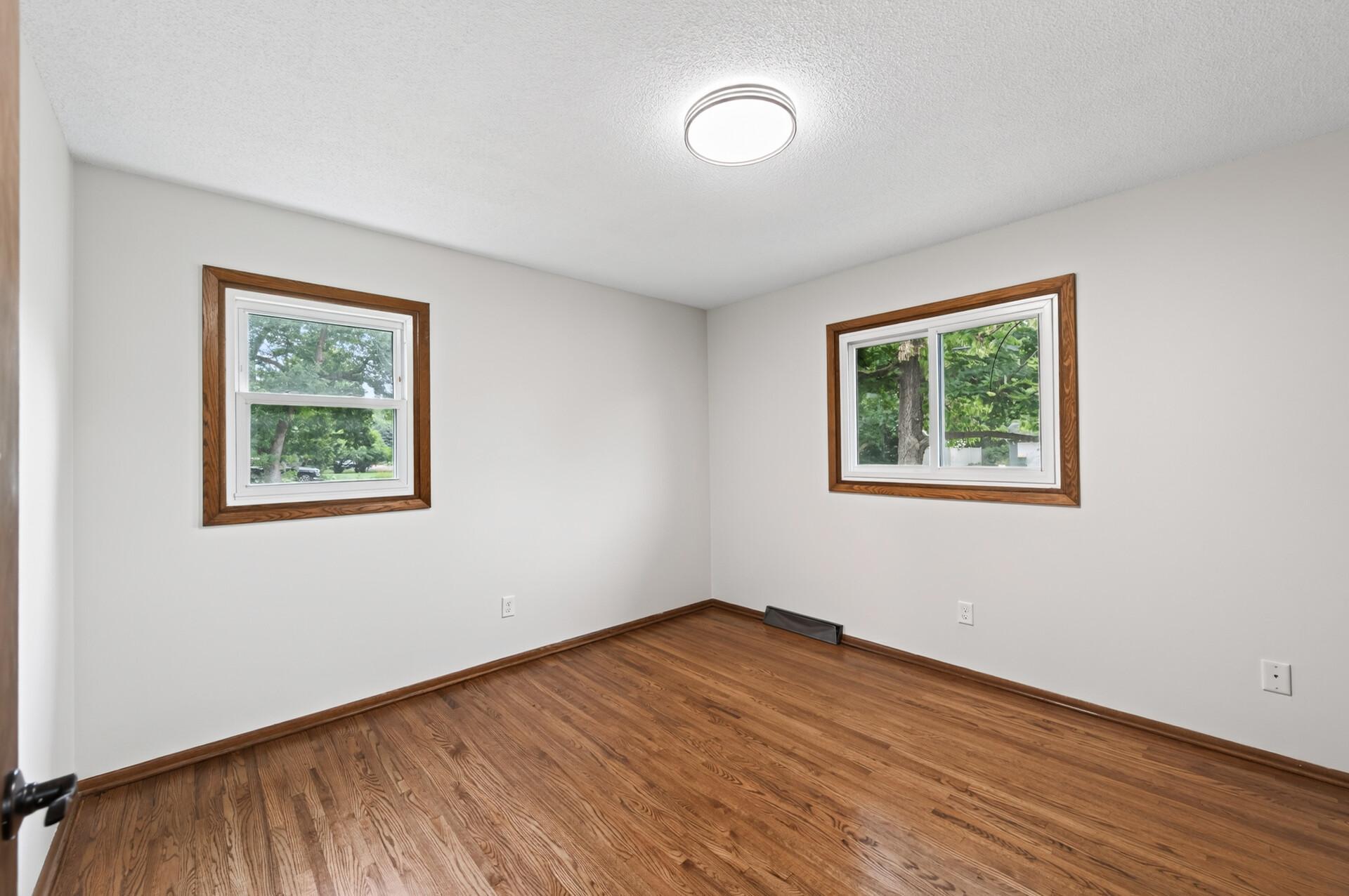 Spacious bedroom with refinished hardwood floors and 2 large windows.