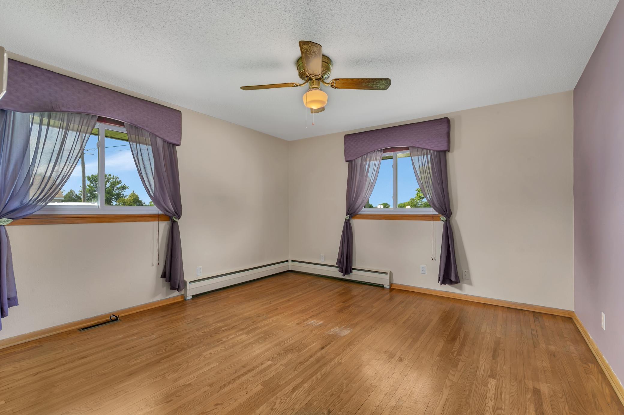 Primary bedroom on main level with ceiling fan and hardwood floors.