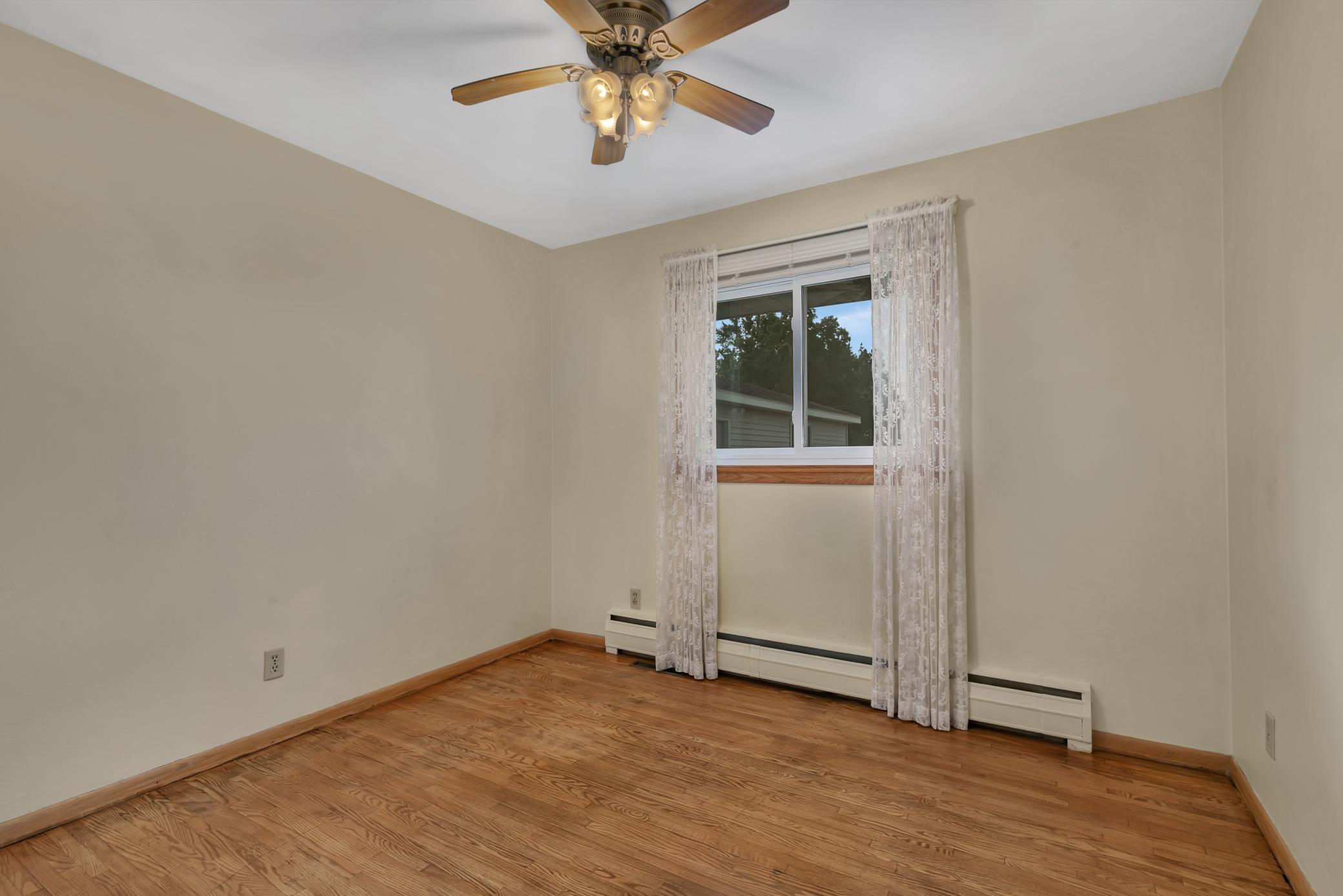 Second main level bedroom with ceiling fan and hardwood floors.