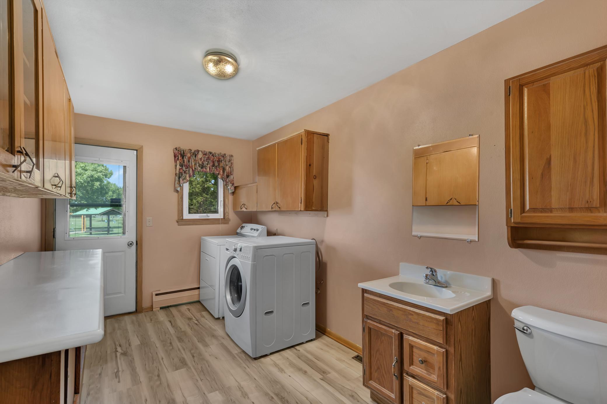 Combo laundry room plus half bathroom which includes an LG front-load washer, Kenmore front-load dryer, folding table, and storage cabinets.