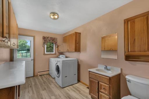 Combo laundry room plus half bathroom which includes an LG front-load washer, Kenmore front-load dryer, folding table, and storage cabinets.