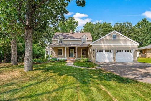 Attractive landscaping, expansive front covered porch, large driveway, mature trees, and sidewalks at the street!
