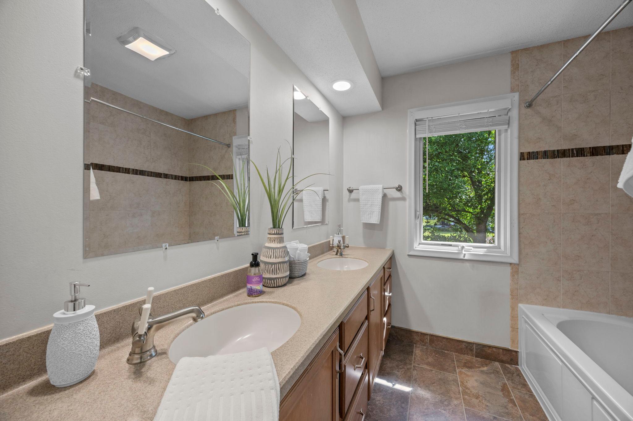 The shared upper-level bathroom features a double vanity, tile flooring, and hall closet storage.