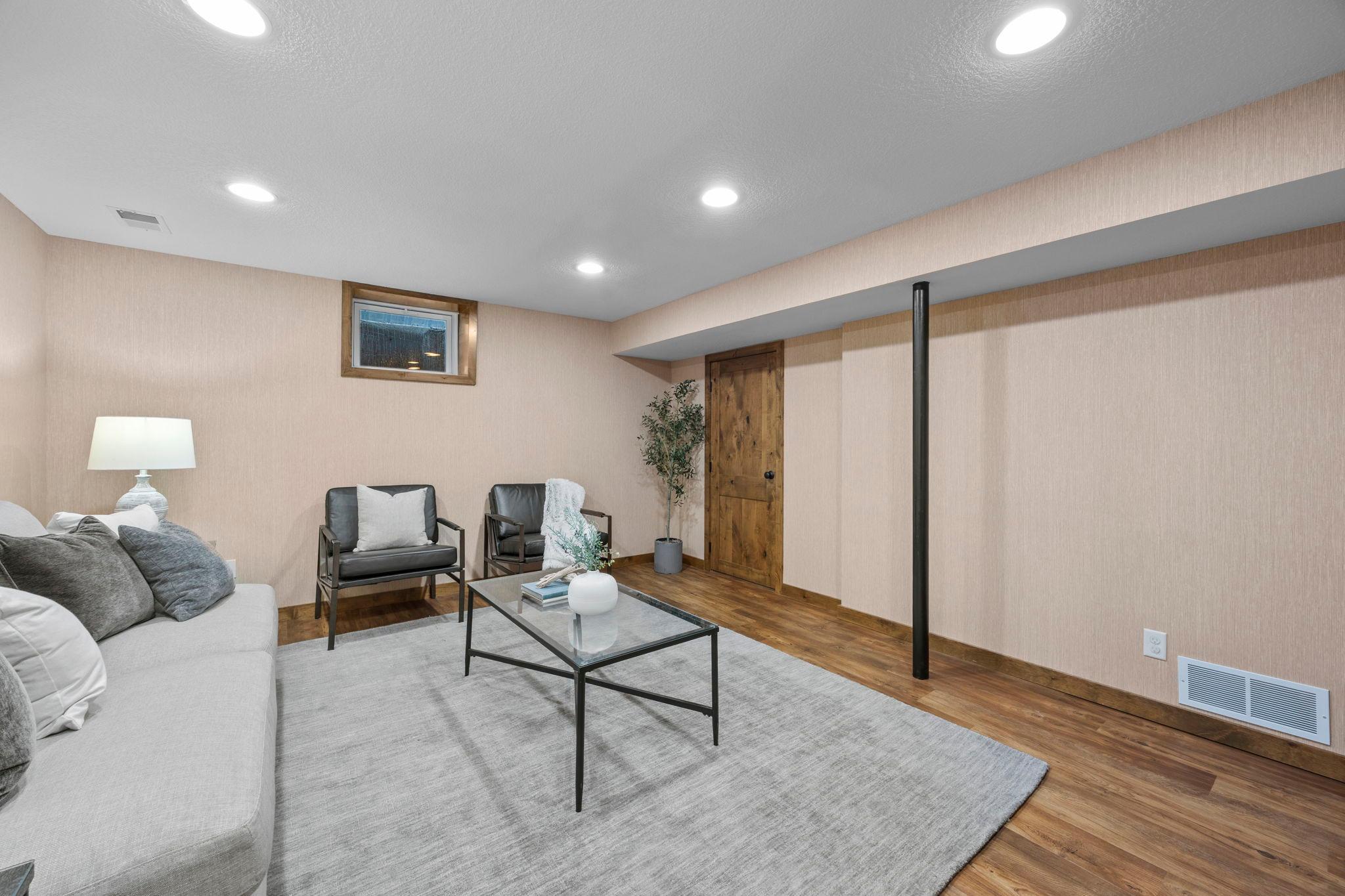 A cozy recreation room with recessed lighting creates an inviting spot for entertaining or relaxing, with a finished 9x8 storage space that adds valuable room for organization.