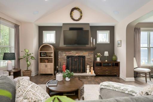 Light filled living room with vaulted ceiling & gas fireplace.