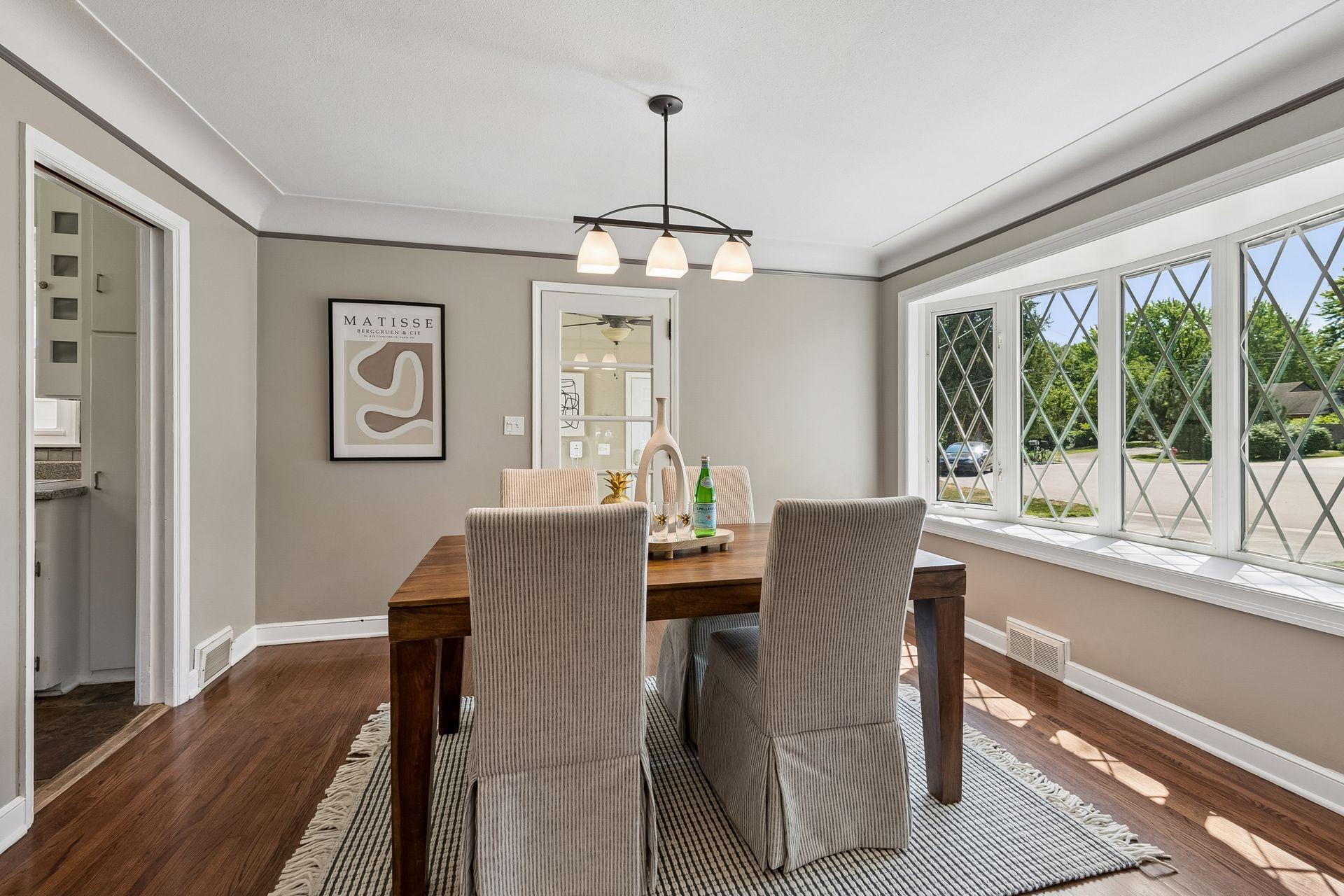 13x10 main-floor dining room with hardwood floors, white enameled trim, and coved ceilings. South-facing windows.