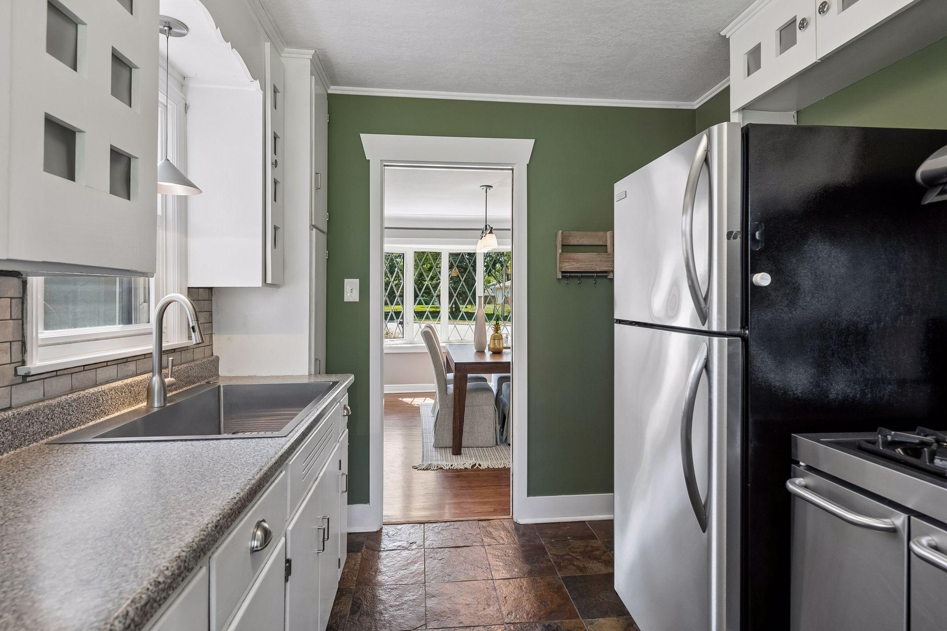 12x8 Main Floor Kitchen with White Cabinetry, Stainless appliances, lighted open shelving, and slate tile flooring. East and north-facing windows.