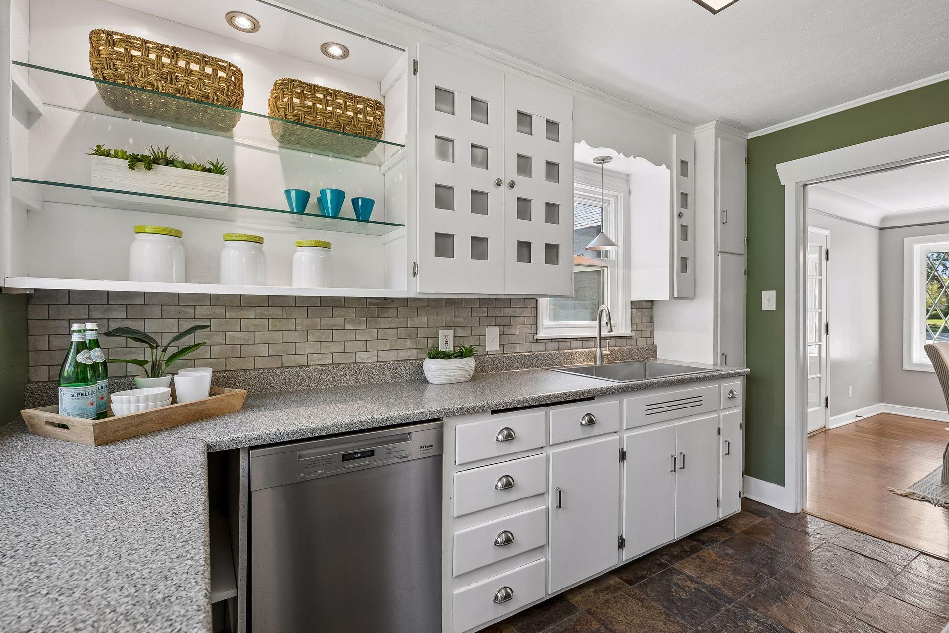 12x8 Main Floor Kitchen with White Cabinetry, Stainless appliances, lighted open shelving, and slate tile flooring. East and north-facing windows.