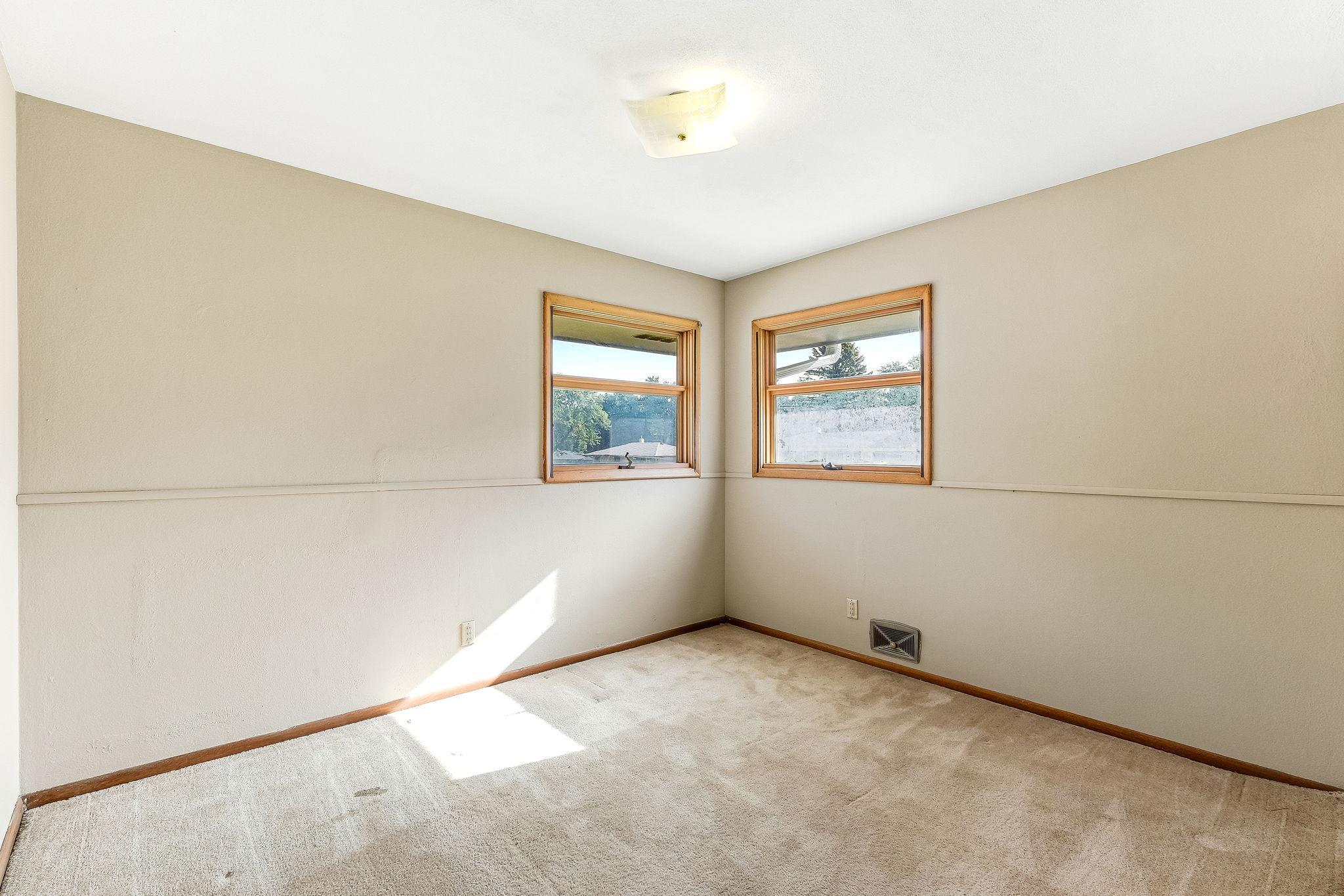 Main floor bedroom with hardwood flooring under carpet.