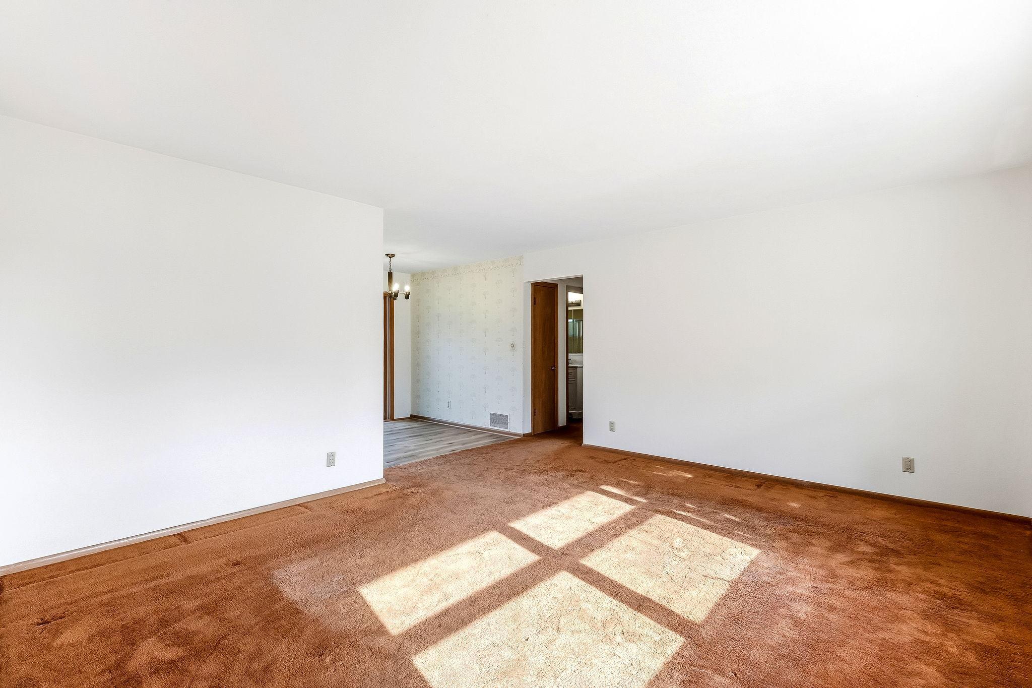 Main floor living room with original wood flooring under carpet.