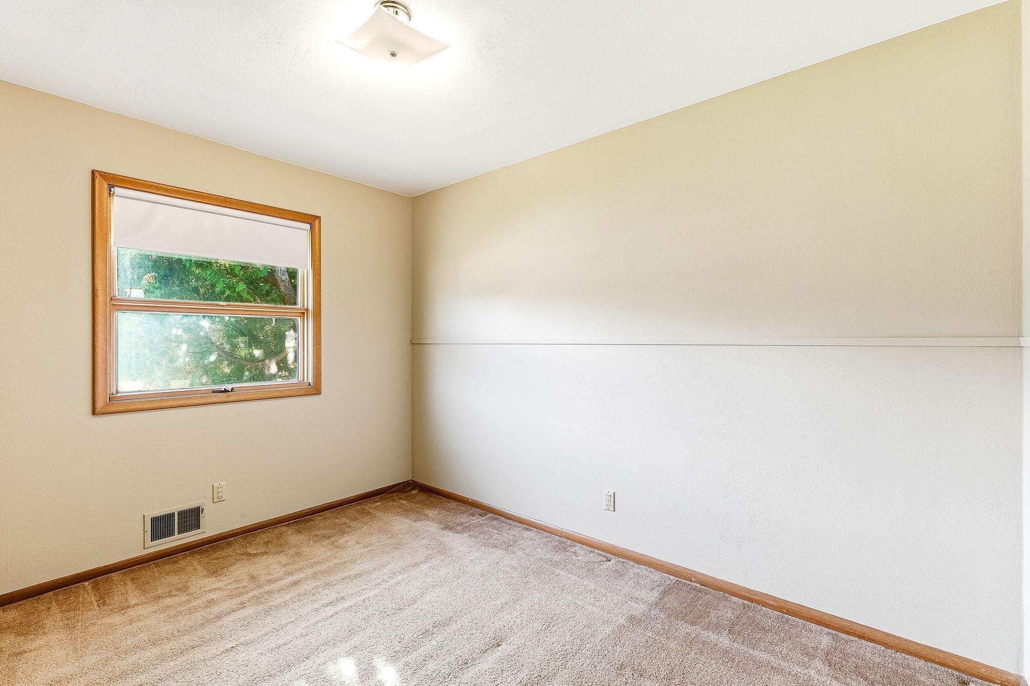 Main floor bedroom with hardwood flooring under carpet.