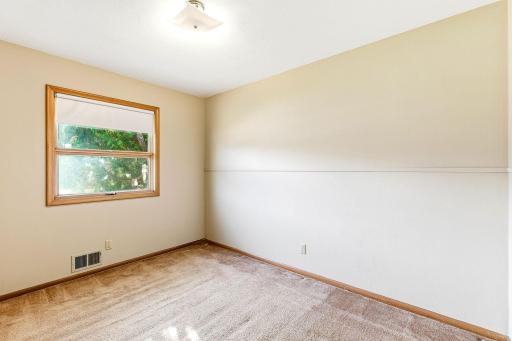 Main floor bedroom with hardwood flooring under carpet.