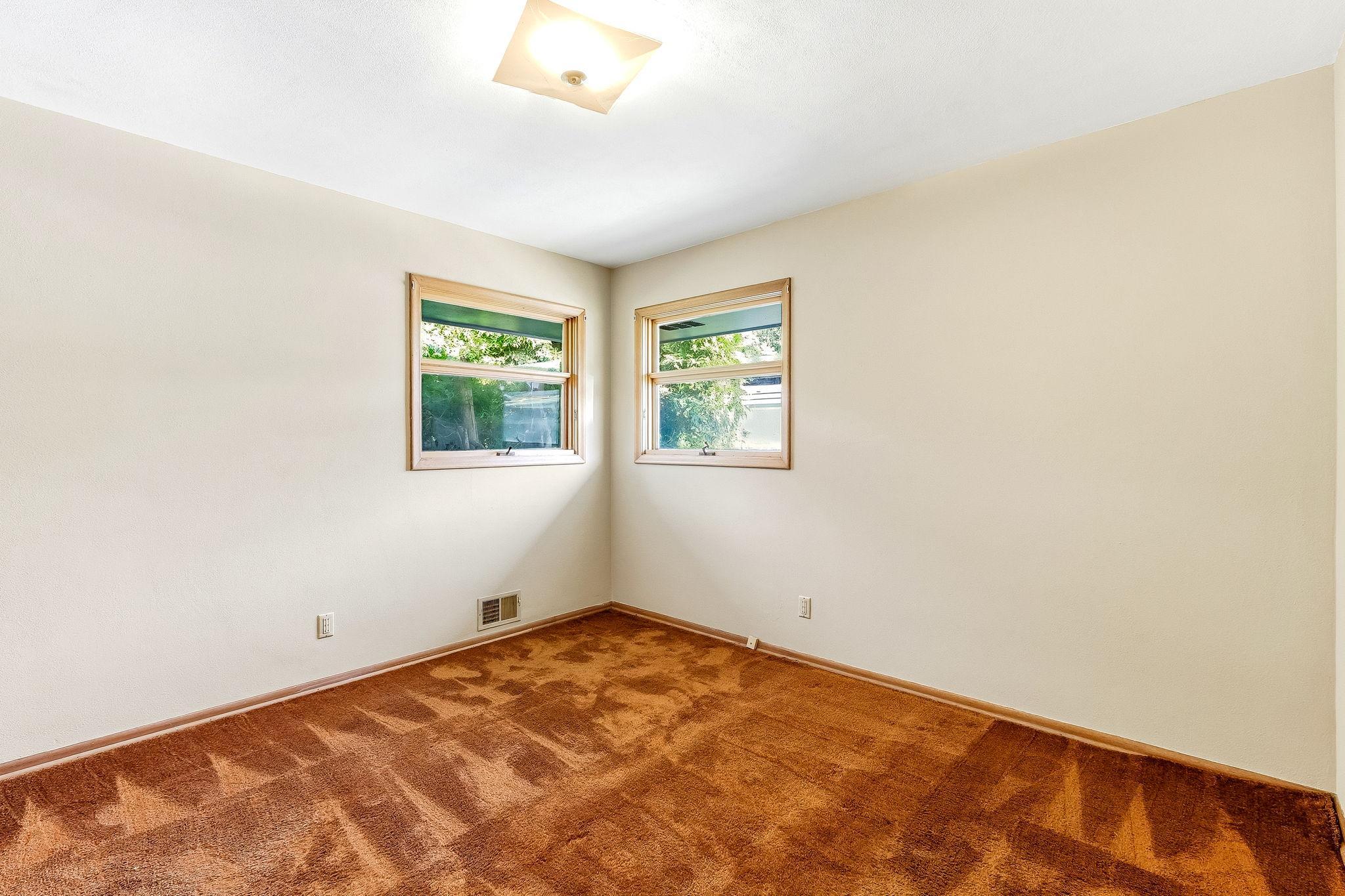 Main floor bedroom with hardwood flooring under carpet.