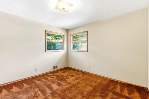 Main floor bedroom with hardwood flooring under carpet.