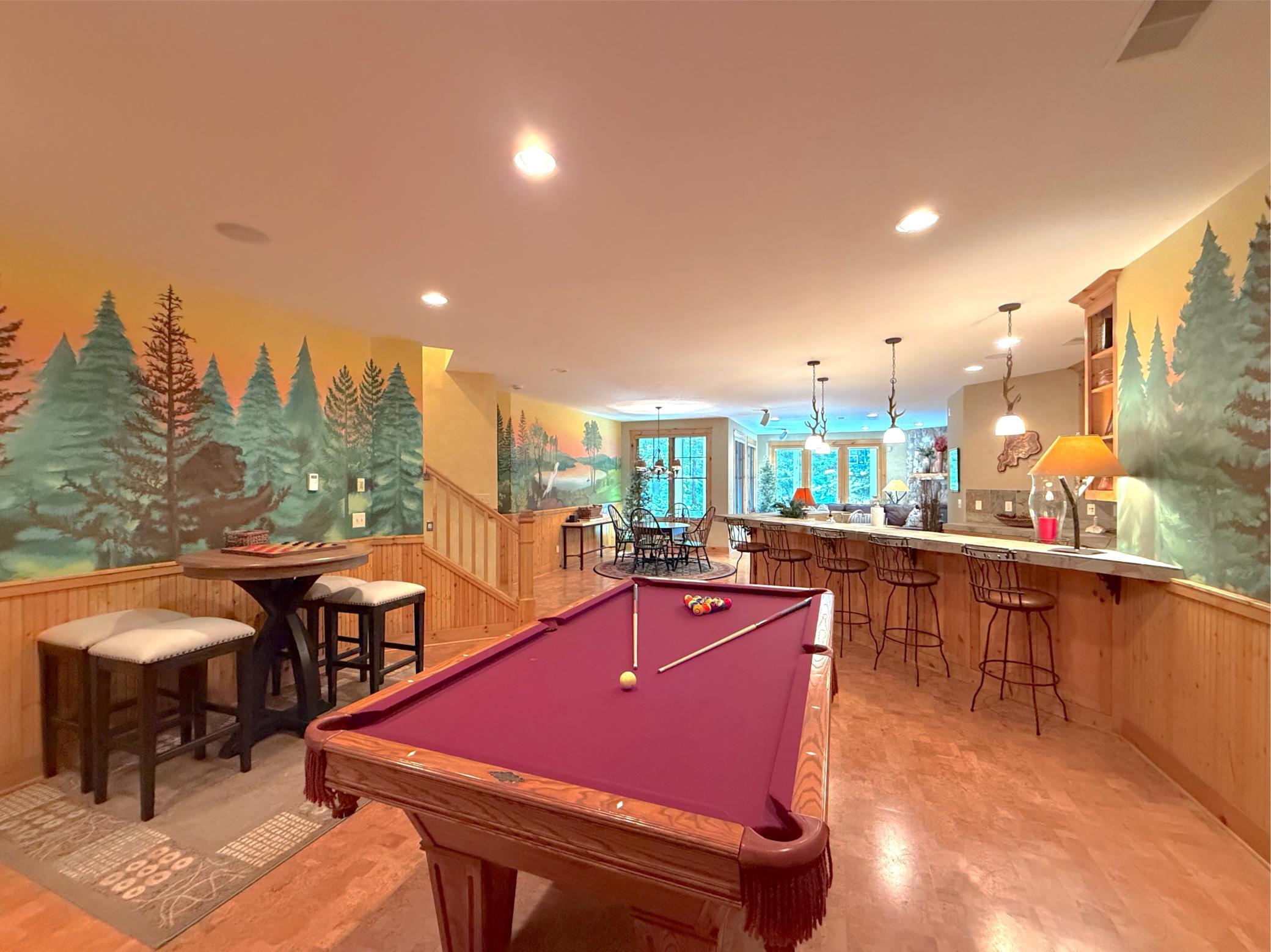 Surrounded with hand painted walls the entertainment room opens to the bar and family room.