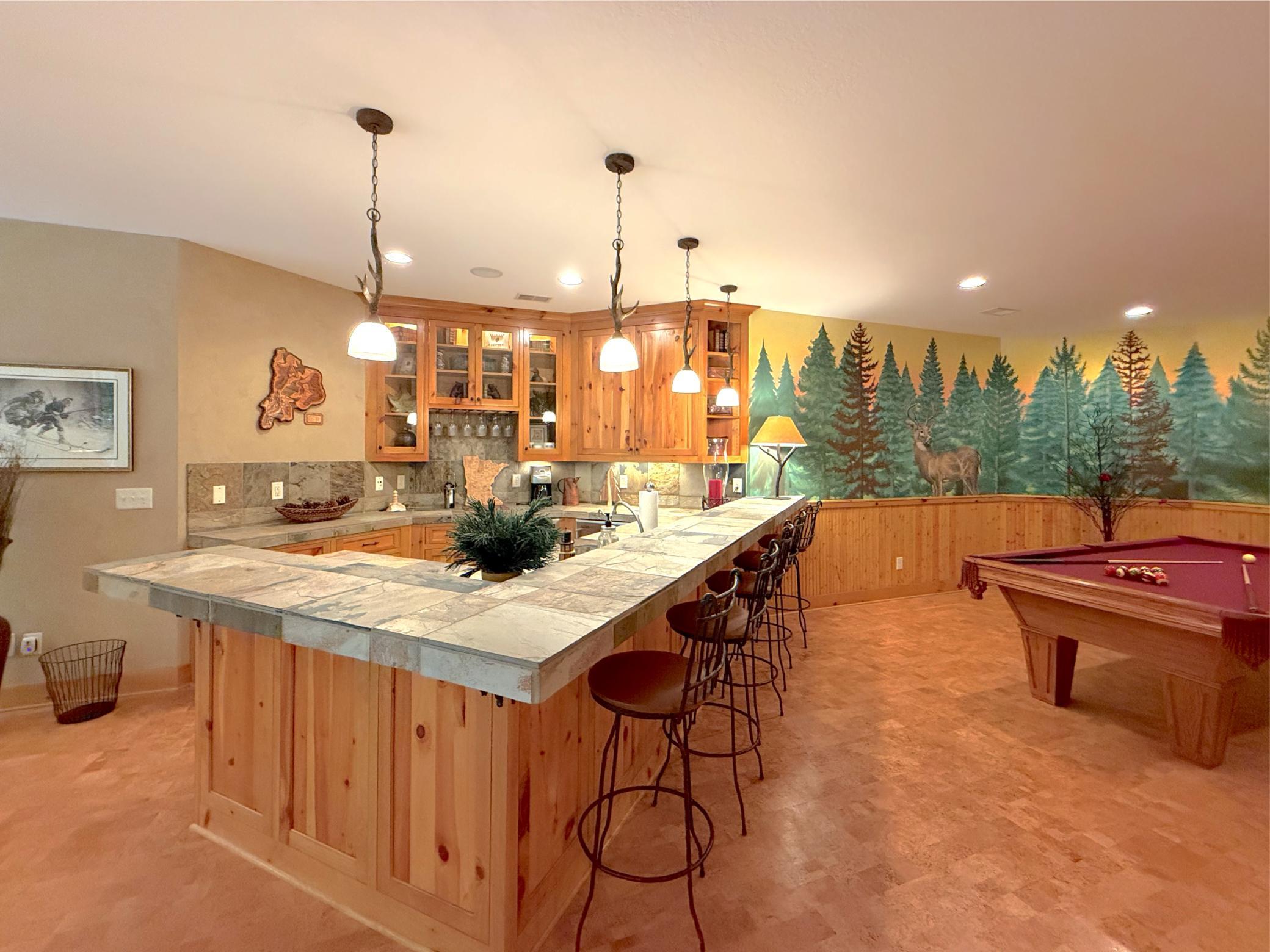 Friends wont want to leave their barstool at this gorgeous wet bar lit by high-end pendant lights.