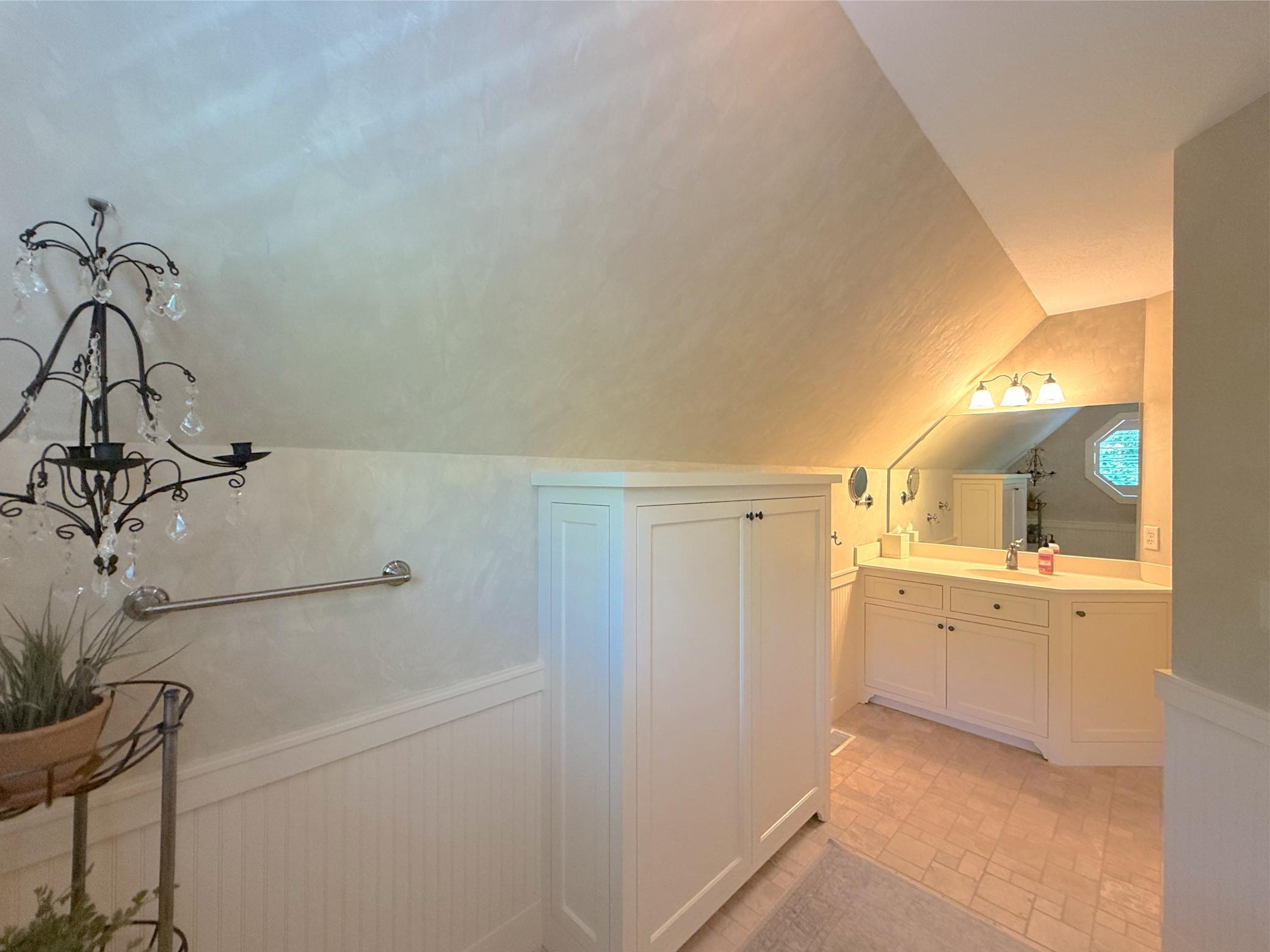 The private three-quarter bathroom offers tile flooring and unique ceiling angles offering character to this bathroom.
