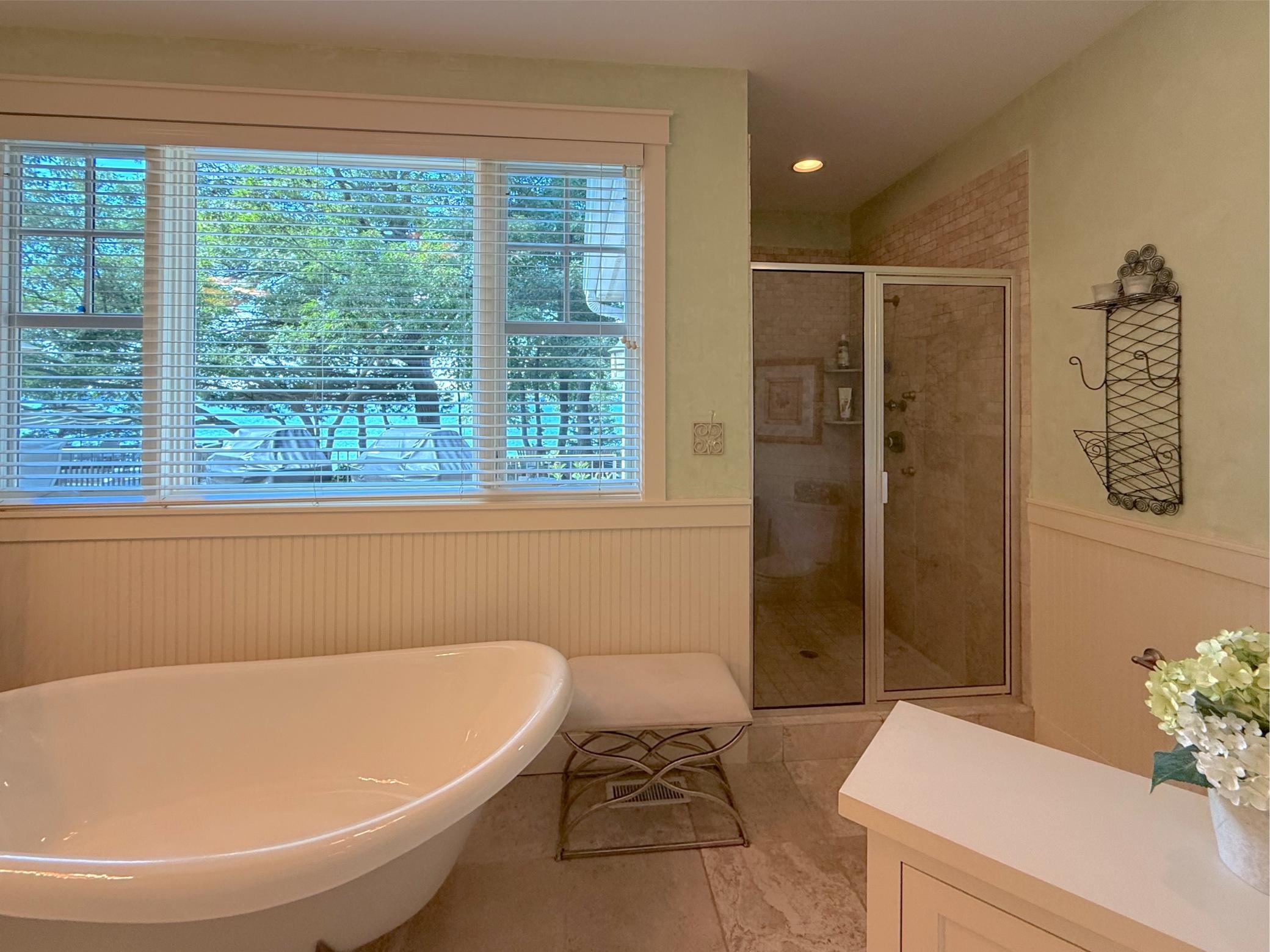 The private primary bathroom is finished wth a separate shower complete with tile surround, custom wood accents and tile flooring.