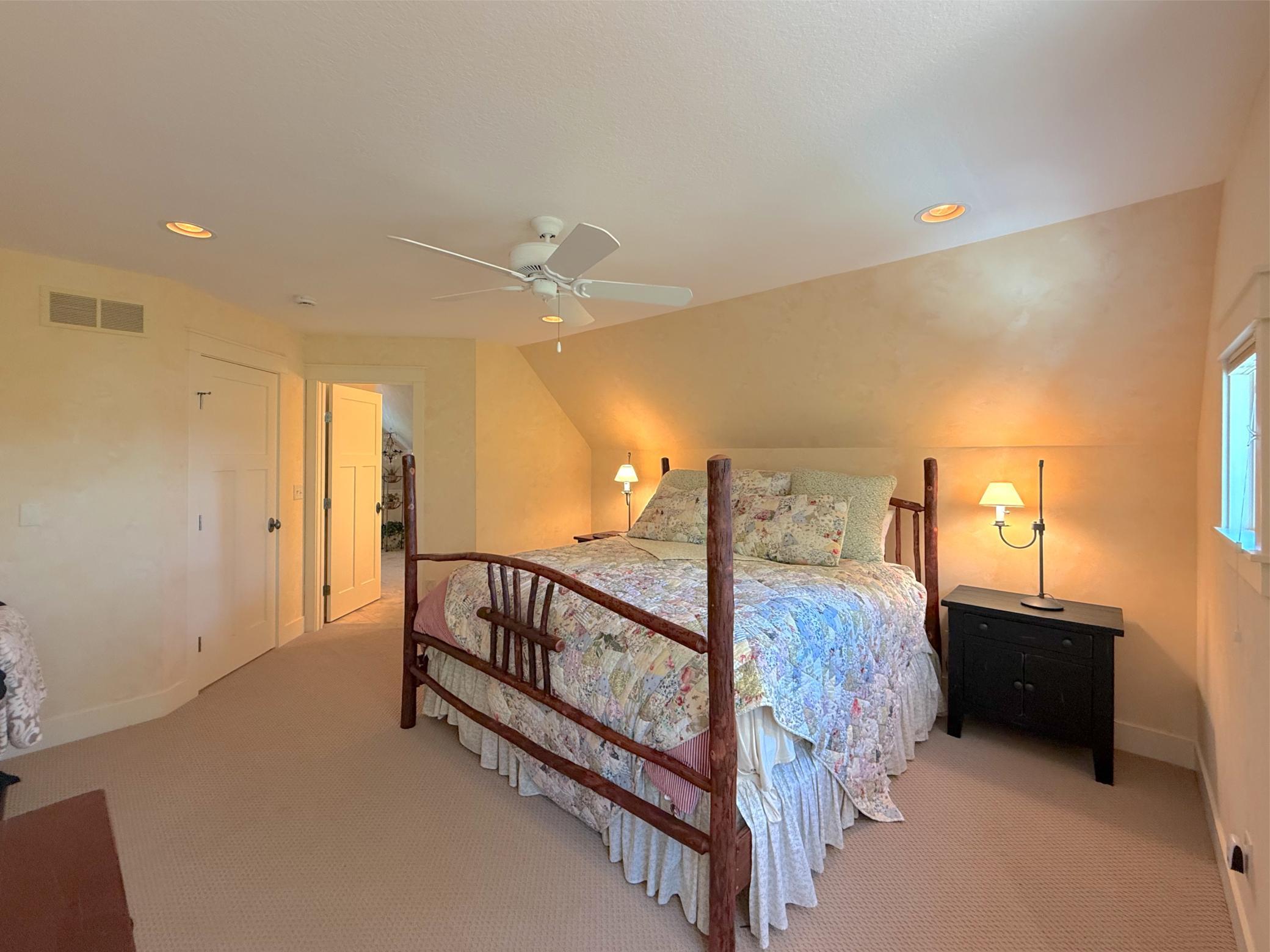 The room is finished with bright walls, plush carpeting, ceiling fan, large closet and entrance to a private bathroom.