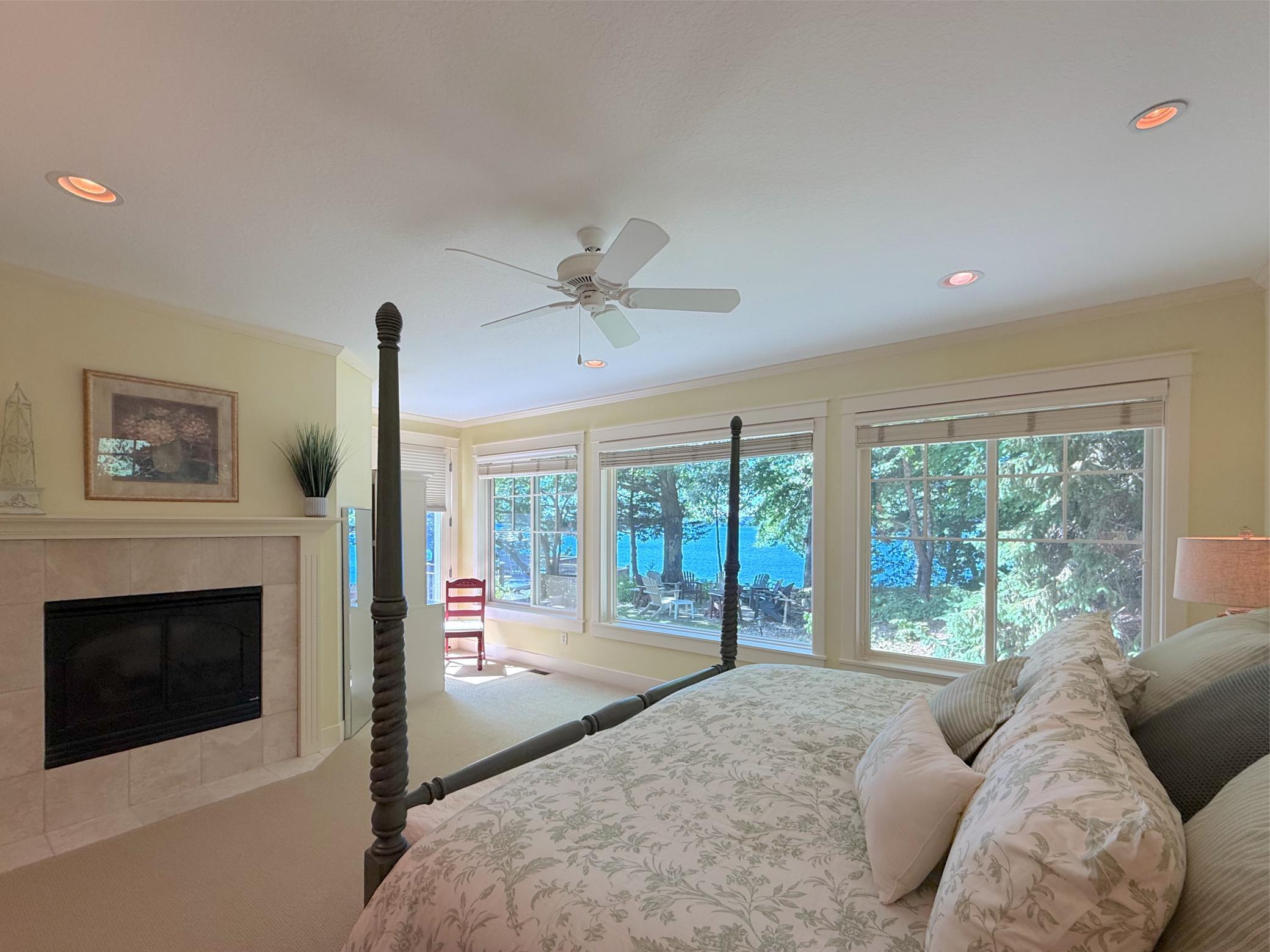 Retreat for the night in the spacious main level primary suite warmed by a gas fireplace with tile accents and a ceiling fan.