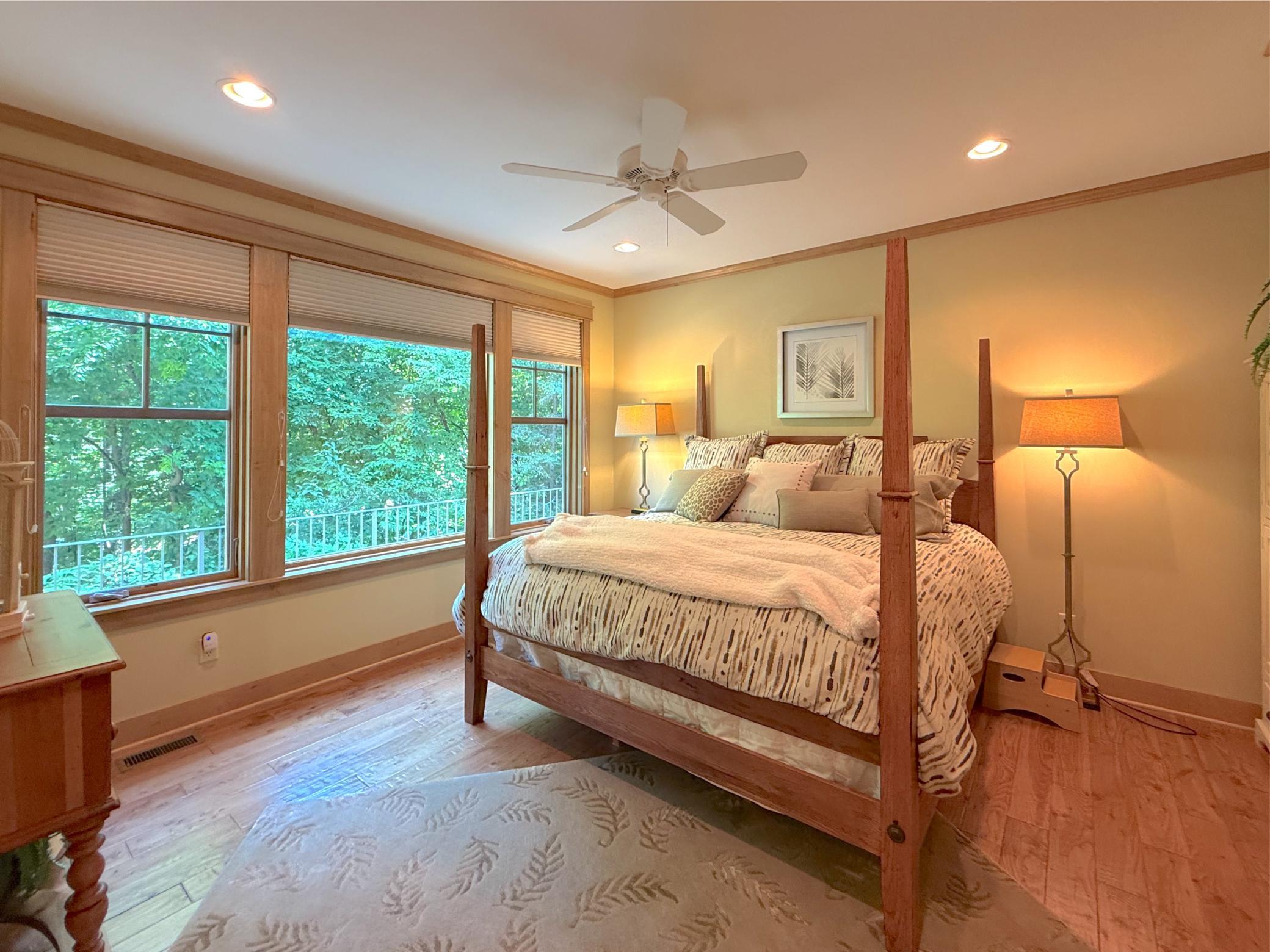 An addition to the primary, this main level bedroom includes a wall of windows and a walk-through 3-quarter bathroom.